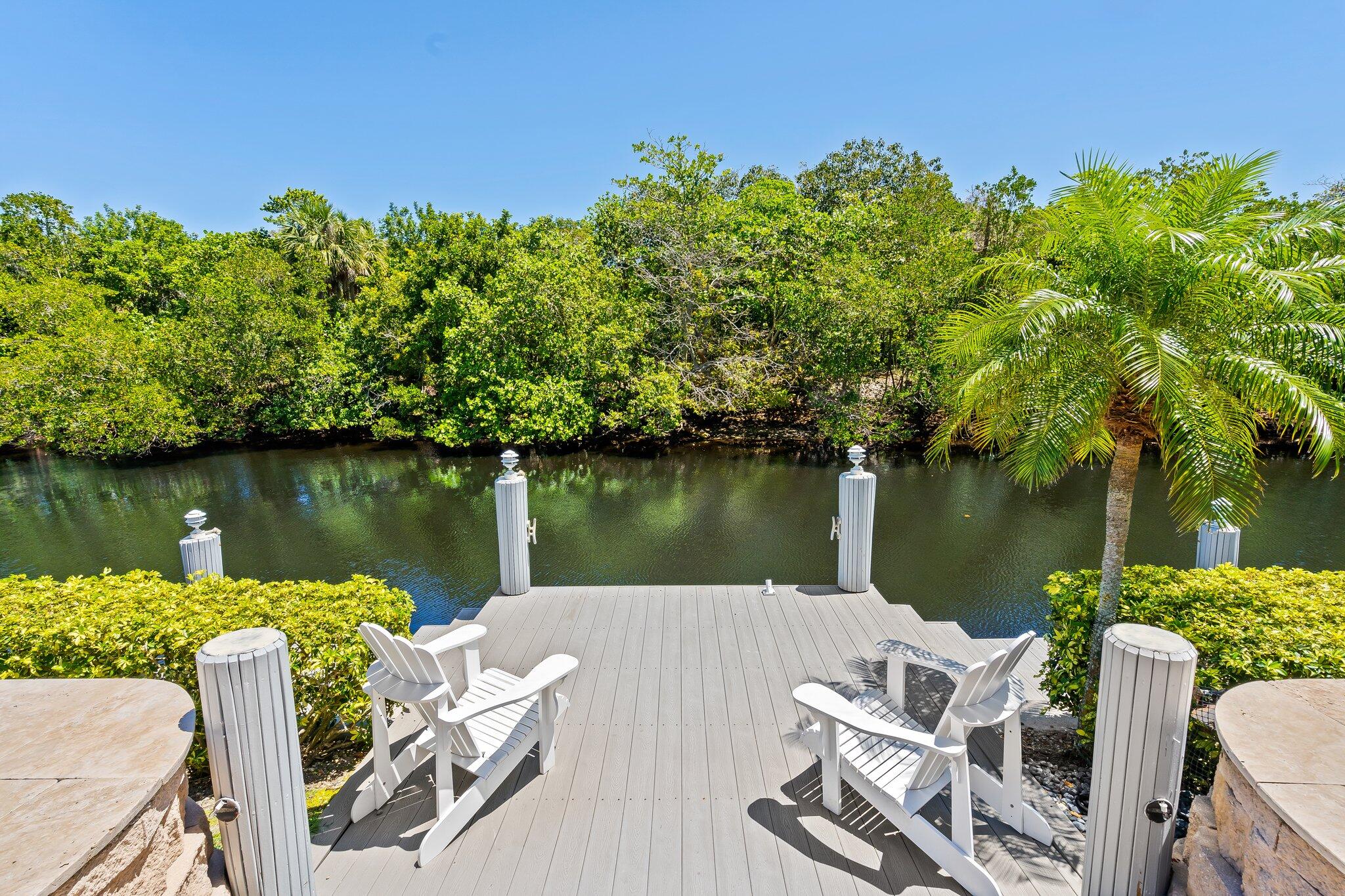 1090 Cypress Way Boca Raton, FL 33486 - Photo 1 of 40 a view of a lake with wooden stairs and bridge and large trees