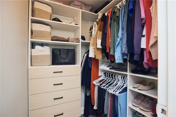 a view of walk in closet with clothes and shoes