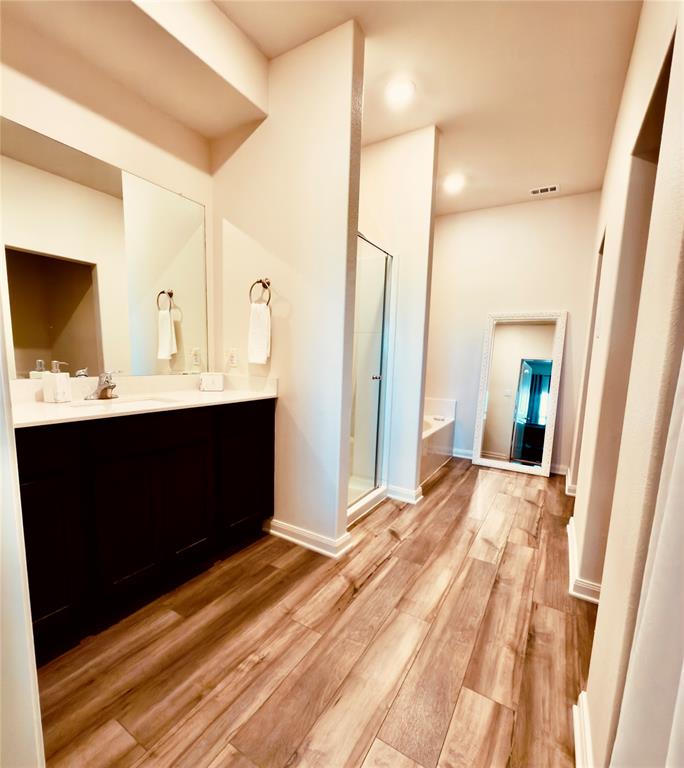 196 Cattlemans Crk Road West Newark, TX 76071 - Photo 8 of 24 Spacious bathroom featuring wood-finish flooring, a double vanity with a light-toned countertop, a frameless glass shower enclosure, and recessed lighting