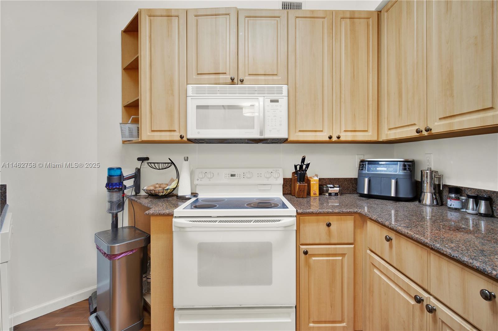 1 Century Lane, Unit 209 Miami Beach, FL 33139 - Photo 24 of 66 a kitchen with granite countertop white cabinets and white appliances