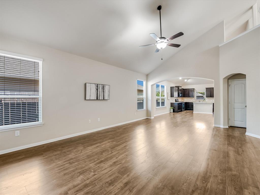 141 Serrano Street Georgetown, TX 78628 - Photo 4 of 7 A spacious living area with vaulted ceilings and beautiful wood flooring flows seamlessly into the kitchen.
