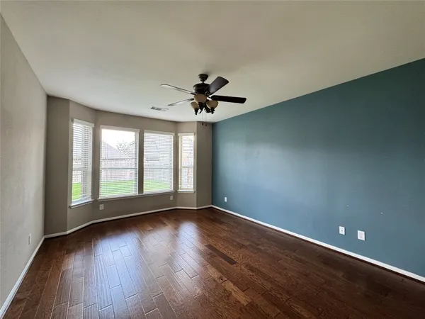 a view of empty room with wooden floor and fan
