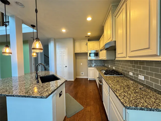 a kitchen with stainless steel appliances granite countertop a sink a stove and a wooden floors
