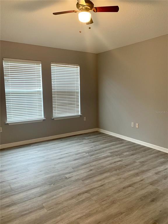 7131 Harmony Square Drive South, Unit 3 Harmony, FL 34773 - Photo 10 of 16 an empty room with wooden floor chandelier fan and windows