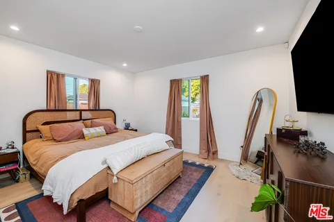 a bedroom with bed mirror and window