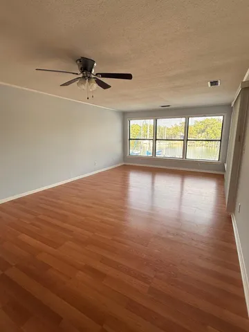 an empty room with wooden floor and windows