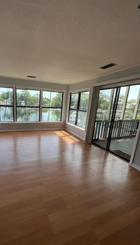 a view of an empty room with wooden floor and a floor to ceiling window