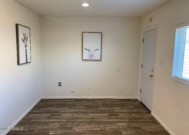 a view of an empty room with wooden floor and window