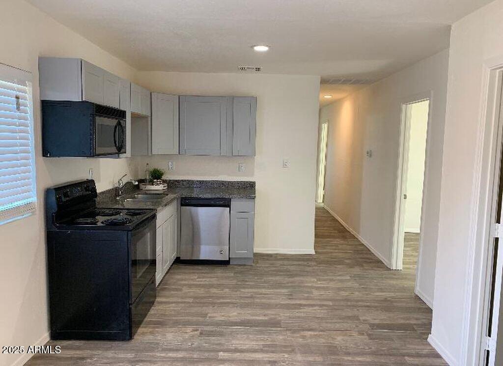 2034 West Madison Street, Unit B Phoenix, AZ 85009 - Photo 4 of 4 a kitchen with granite countertop a stove top oven a sink dishwasher and a refrigerator with wooden floor