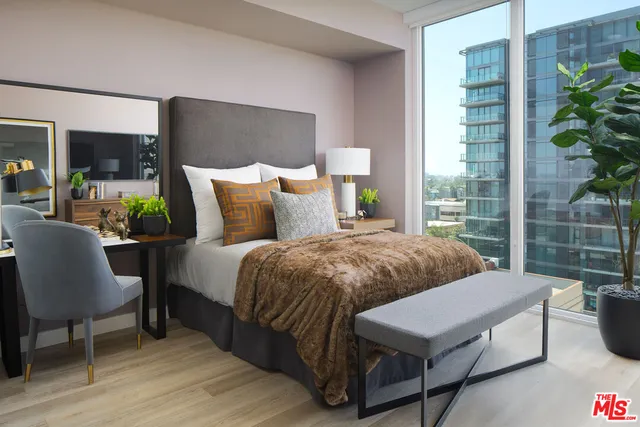 a bedroom with a bed a table and a potted plant