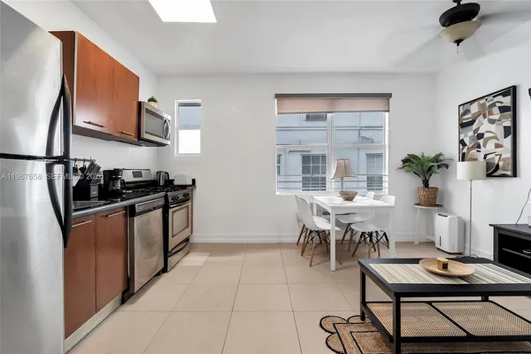 a kitchen with stainless steel appliances kitchen island granite countertop a stove a refrigerator a sink a dining table and chairs with wooden floor