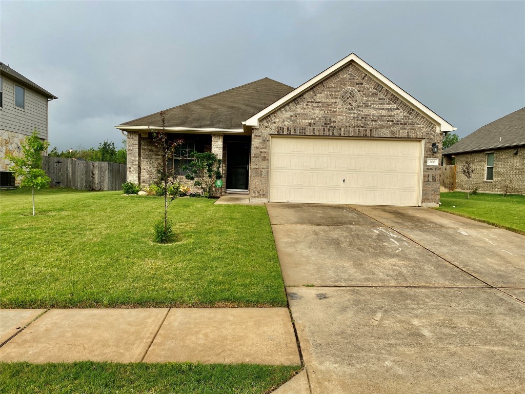 View of front of property featuring brick siding, concrete driveway, an attached garage, and a shingled roof