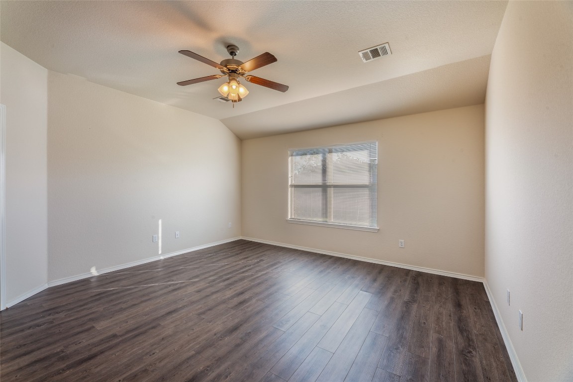 200 Falcon Lane Leander, TX 78641 - Photo 11 of 20 Empty room with dark wood-type flooring, lofted ceiling, and ceiling fan