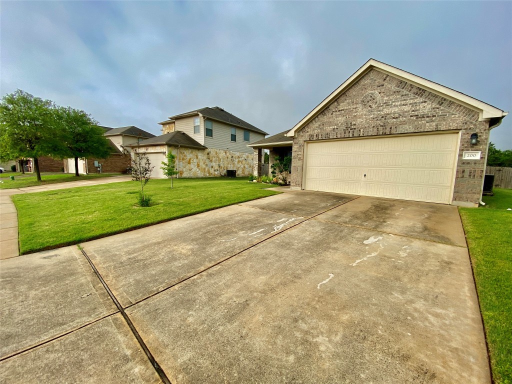 200 Falcon Lane Leander, TX 78641 - Photo 2 of 20 View of front facade featuring brick siding, driveway, an attached garage, and a front yard