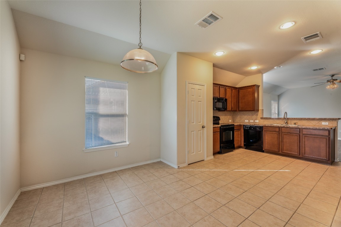 200 Falcon Lane Leander, TX 78641 - Photo 9 of 20 Kitchen with vaulted ceiling, decorative light fixtures, black appliances, brown cabinets, and a ceiling fan