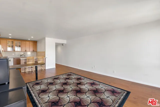 wooden floor with a view of kitchen with granite countertop window