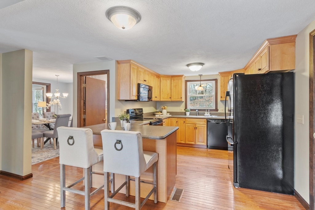 61 Beaver Road Reading, MA 01867 - Photo 10 of 39 a kitchen with a refrigerator a stove a sink a dining table and chairs