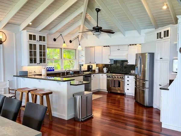 a kitchen with stainless steel appliances granite countertop a refrigerator a stove a sink dishwasher a dining table and chairs with wooden floor