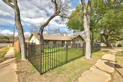 a view of a wrought iron fence with large trees