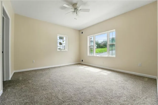 an empty room with windows and ceiling fan