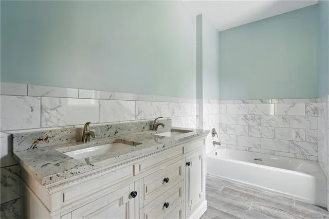 a bathroom with a granite countertop sink a bathtub and mirror