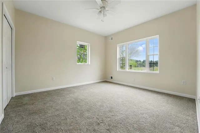 an empty room with windows and ceiling fan