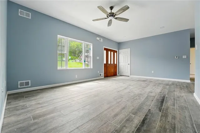 a view of an empty room with a window and wooden floor