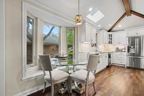 a kitchen with stainless steel appliances a dining table chairs a sink and dishwasher a refrigerator with wooden floor
