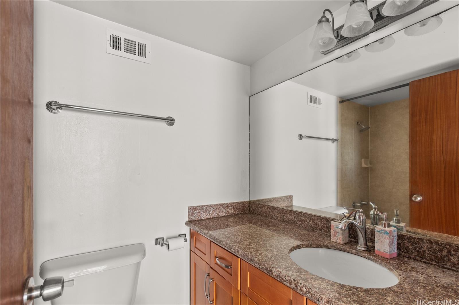 1069 Spencer Street, Unit 101 Honolulu, HI 96822 - Photo 9 of 19 a bathroom with a granite countertop sink and a mirror
