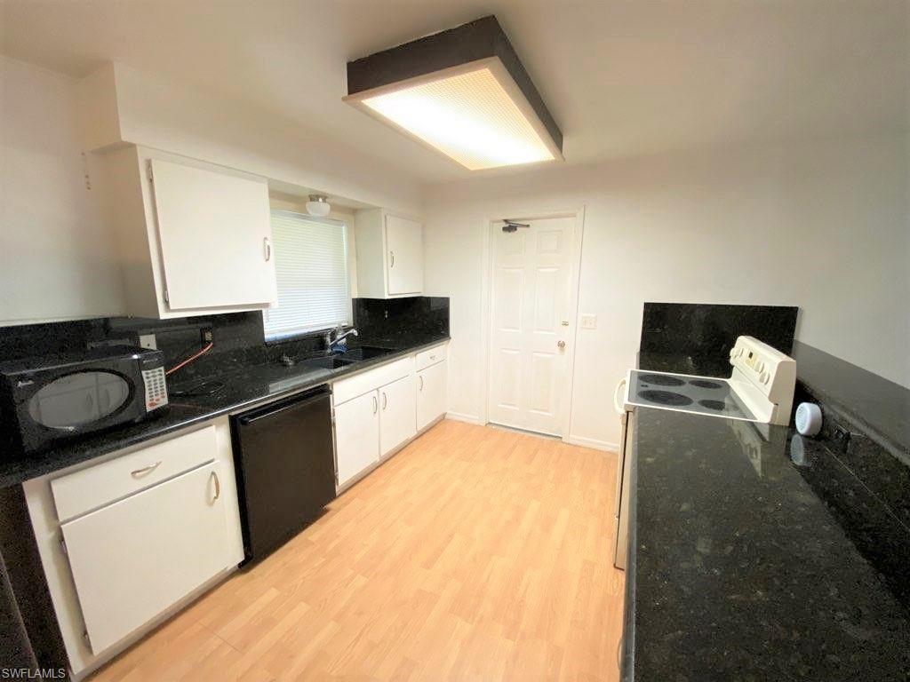 18457 Matanzas Road Fort Myers, FL 33967 - Photo 5 of 9 a kitchen with granite countertop white cabinets and black appliances
