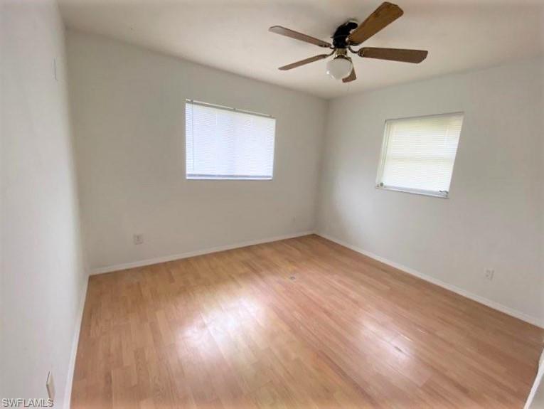 18457 Matanzas Road Fort Myers, FL 33967 - Photo 8 of 9 an empty room with wooden floor ceiling fan and windows
