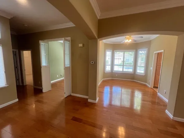 a view of an empty room with wooden floor and a window