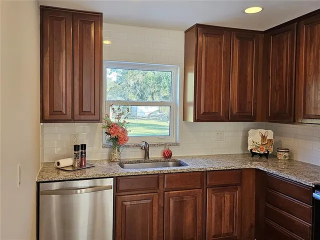 a kitchen with stainless steel appliances granite countertop wooden cabinets a sink and a window