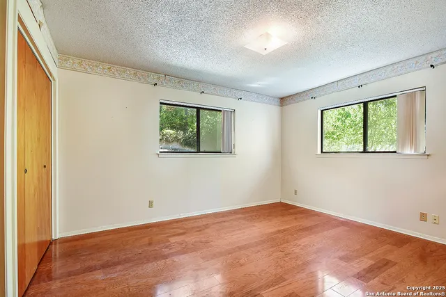 a view of empty room with wooden floor and fan
