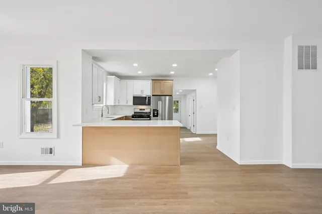 a view of kitchen with kitchen island a sink wooden floor and a refrigerator