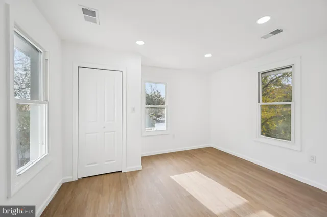 an empty room with wooden floor and windows