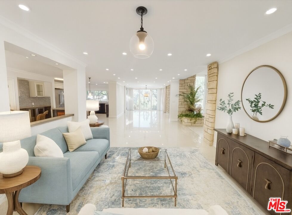 1743 Stone Canyon Road Los Angeles, CA 90077 - Photo 6 of 28 a living room with furniture a fireplace and a chandelier