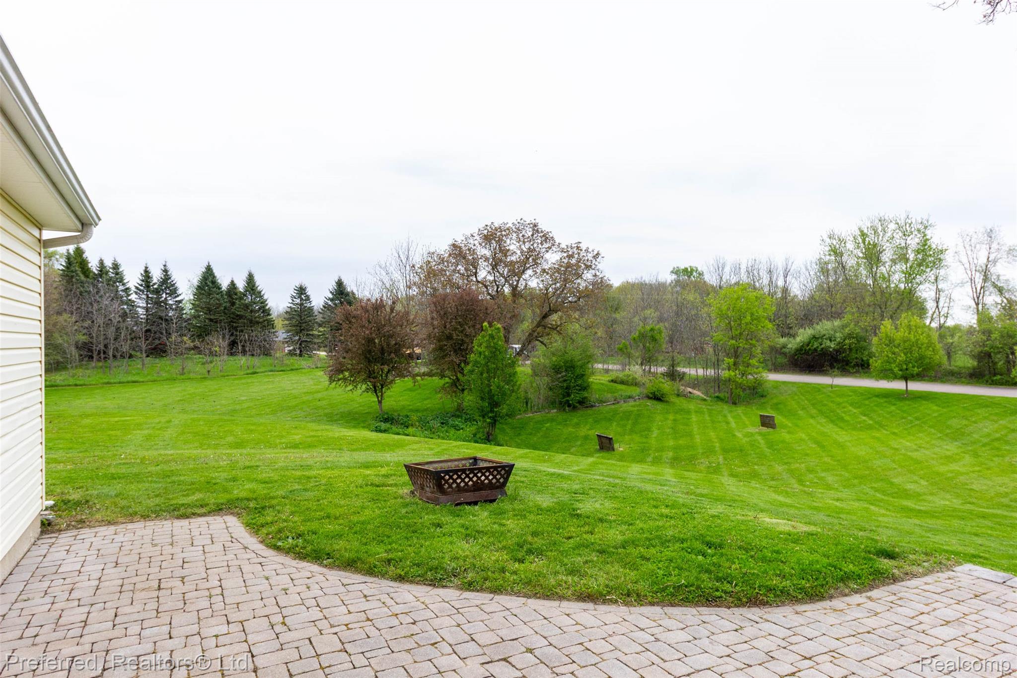 9840 Currie Road Northville, MI 48167 - Photo 43 of 62 View of grassy yard with an outdoor fire pit