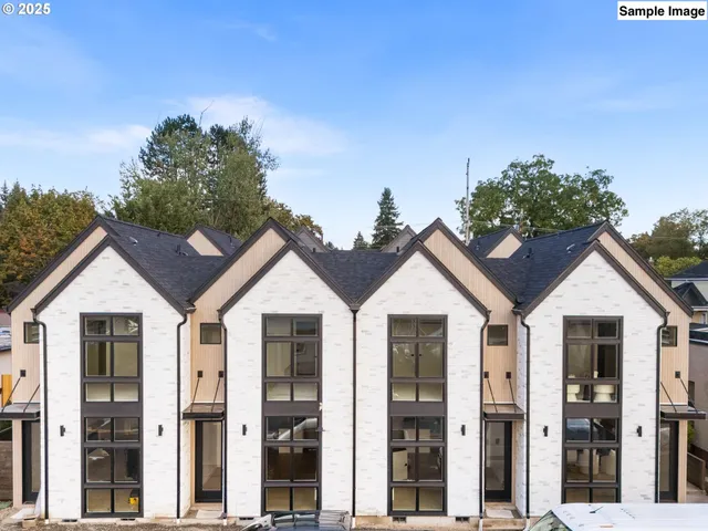 a view of a white house with a small yard and large trees