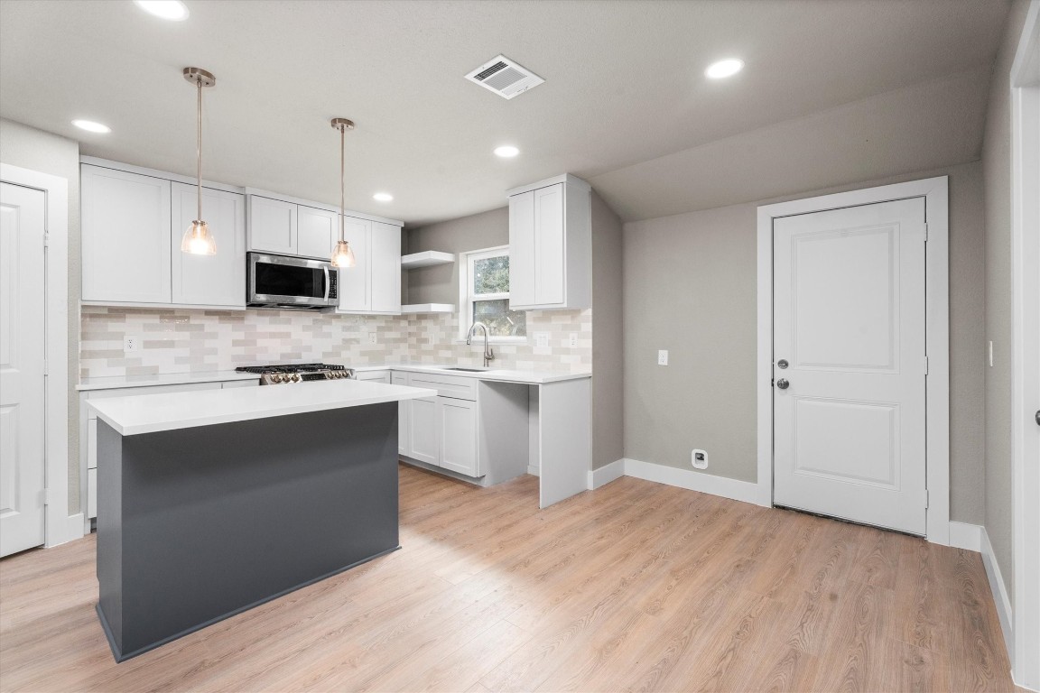 6162 Beldart Street Houston, TX 77033 - Photo 14 of 36 a large kitchen with kitchen island a sink stainless steel appliances and white cabinets