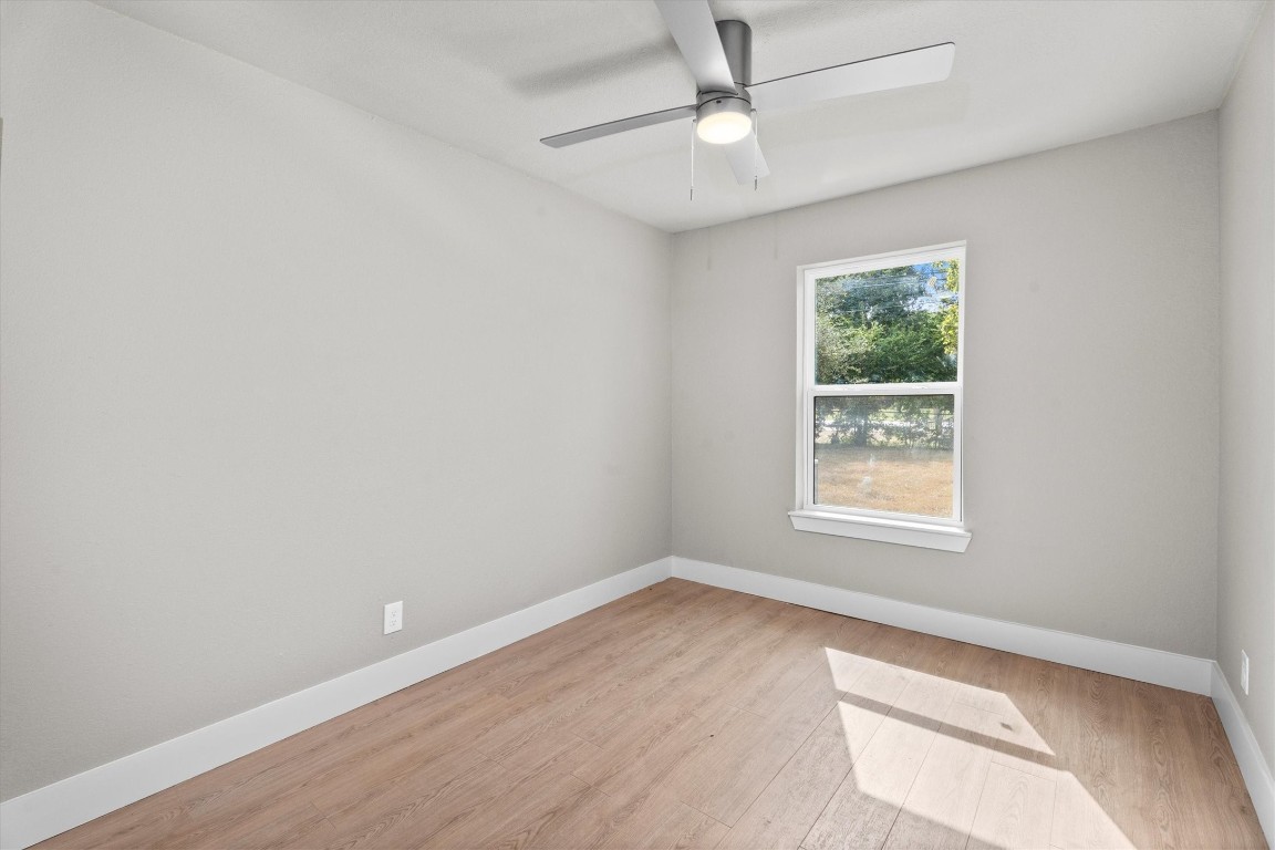 6162 Beldart Street Houston, TX 77033 - Photo 18 of 36 an empty room with wooden floor chandelier fan and windows