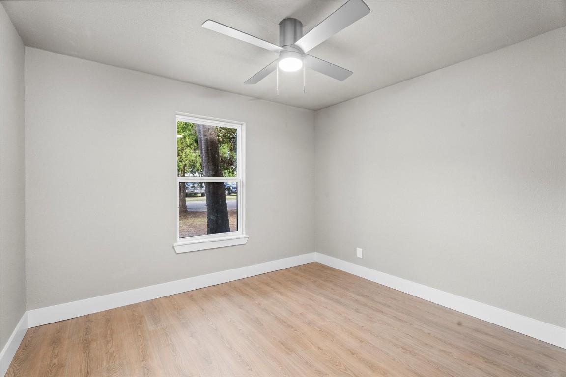 6162 Beldart Street Houston, TX 77033 - Photo 21 of 36 an empty room with wooden floor chandelier fan and windows