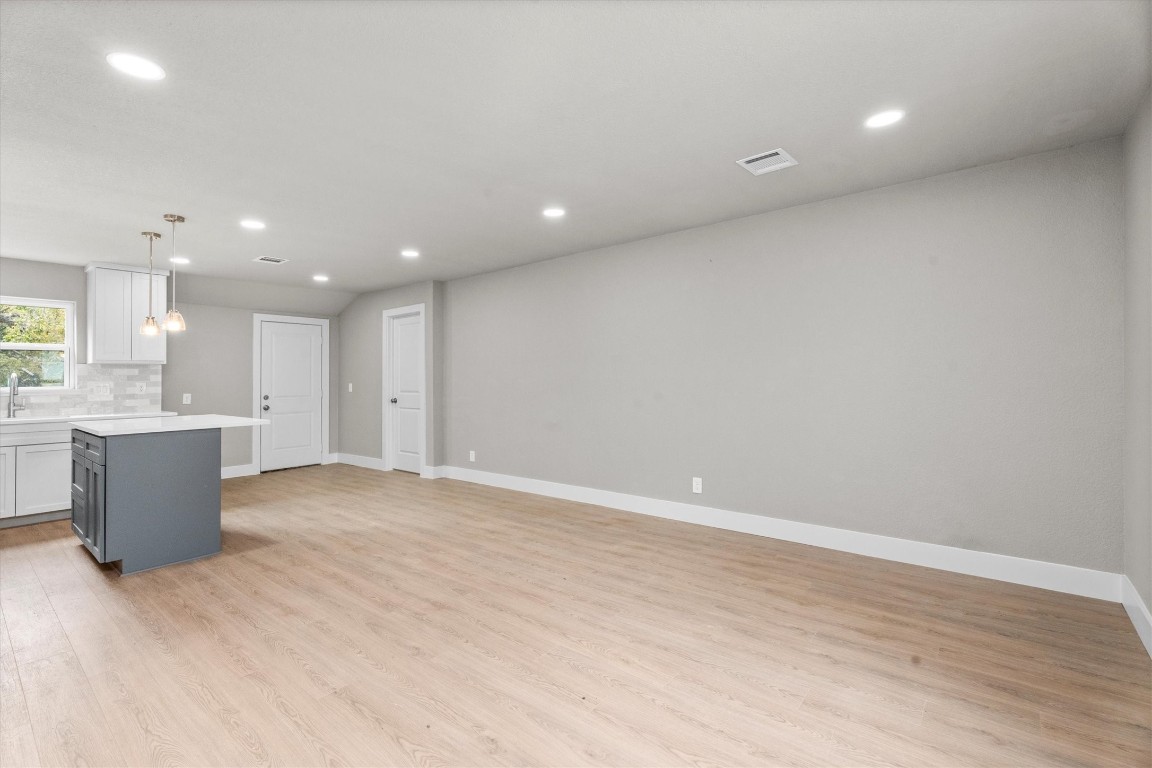 6162 Beldart Street Houston, TX 77033 - Photo 5 of 36 an empty room with wooden floor and a kitchen