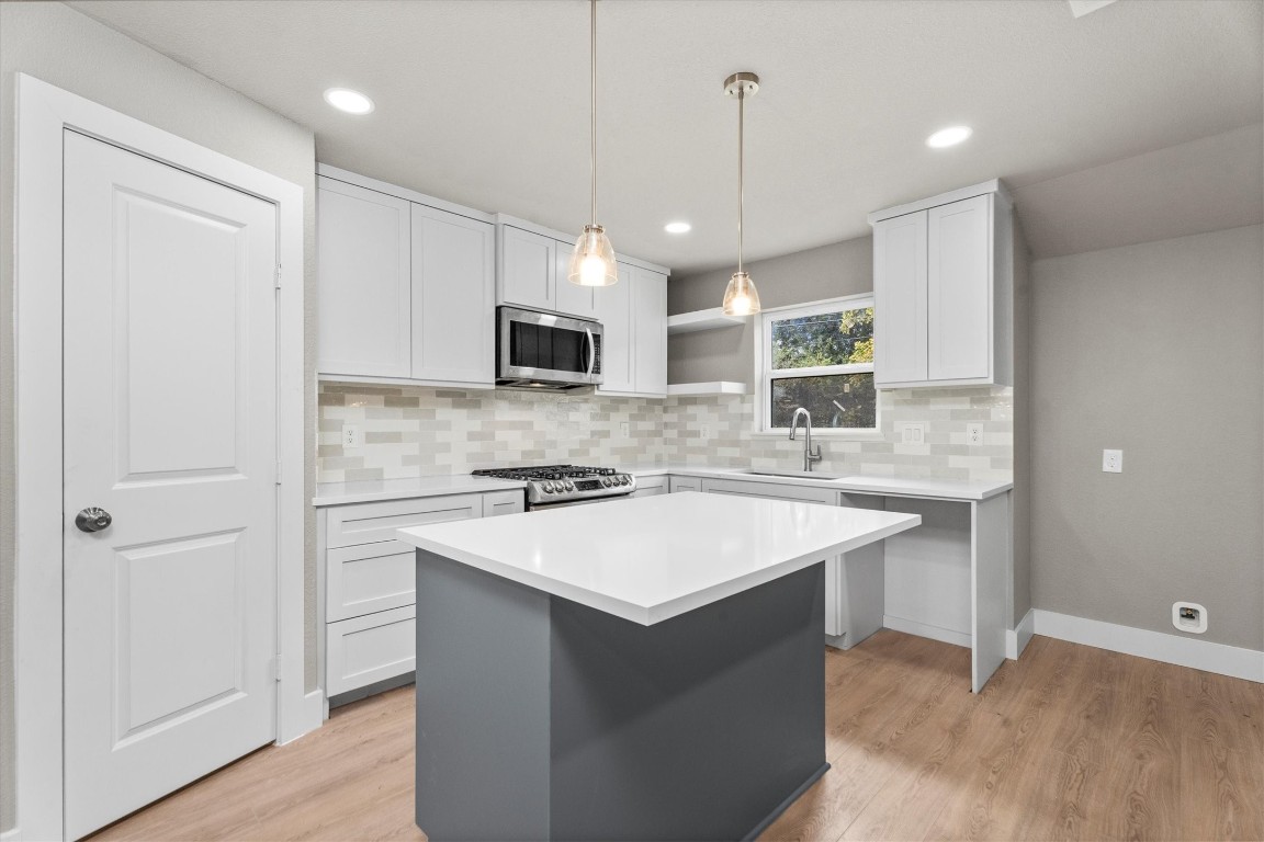 6162 Beldart Street Houston, TX 77033 - Photo 10 of 36 a kitchen with a sink a center island a stove a refrigerator cabinets and a window