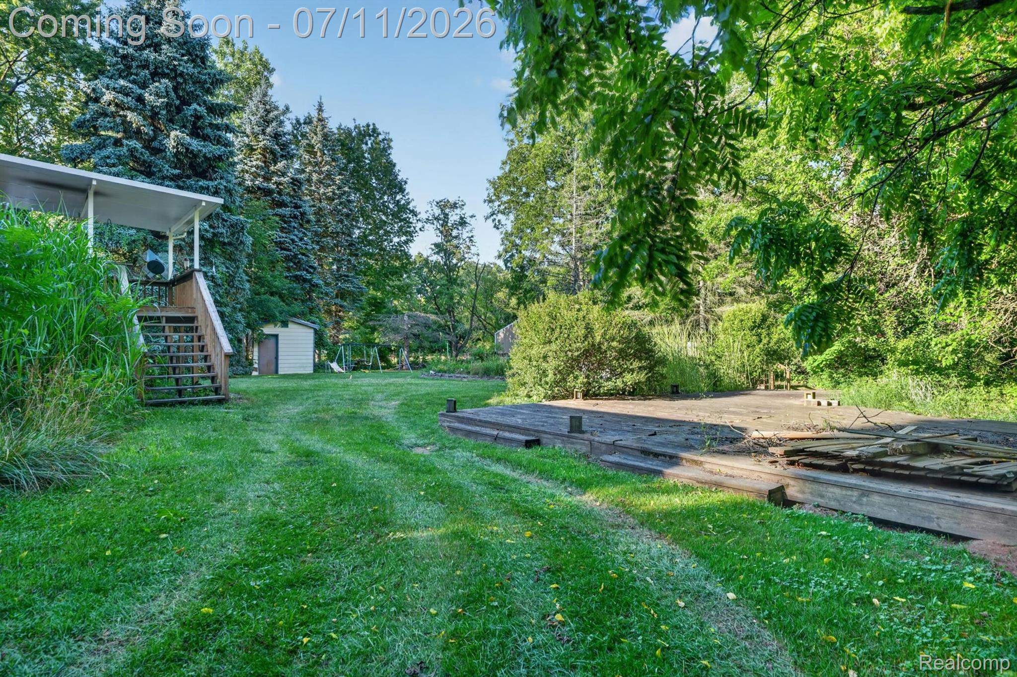 4430 North Center Road Flint, MI 48506 - Photo 46 of 49 Expansive grassy yard area featuring a multi-level wooden deck structure, a covered porch with wooden stairs, and a detached storage shed