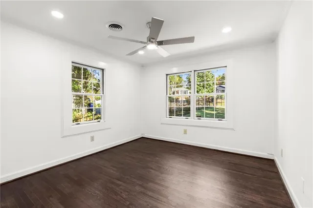 an empty room with wooden floor chandelier fan and windows