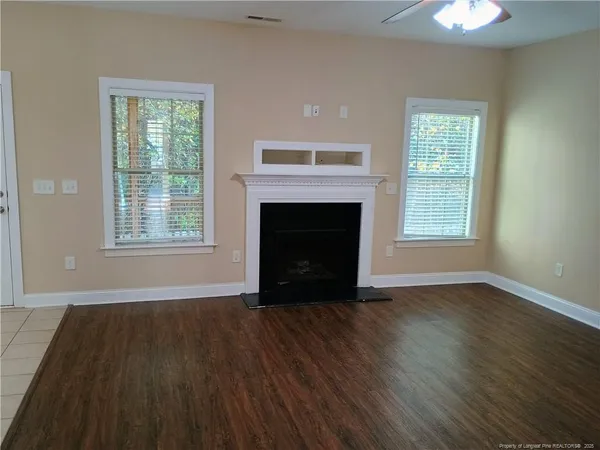 wooden floor fireplace and windows in an empty room