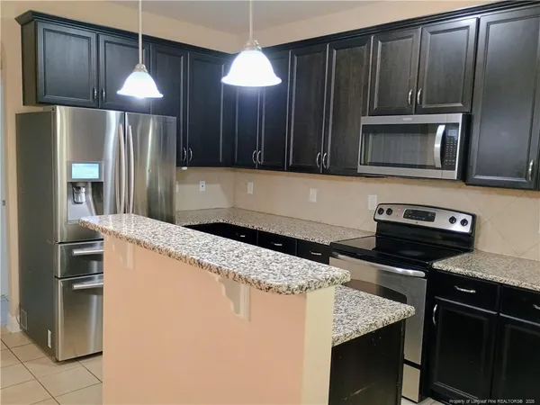 a kitchen with granite countertop a refrigerator stove and microwave