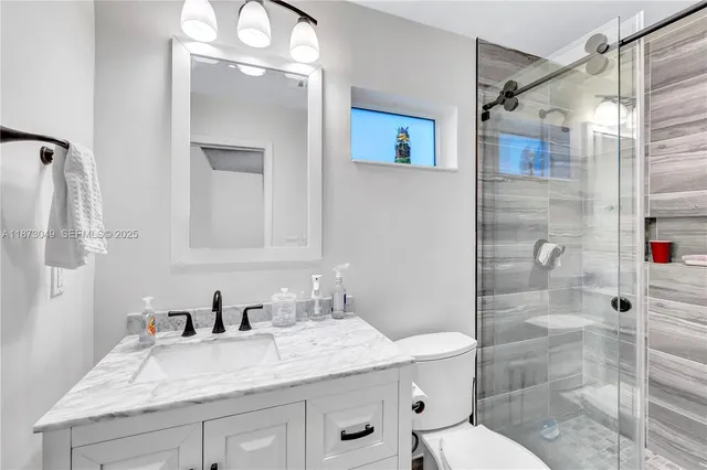 a bathroom with a granite countertop sink toilet and shower