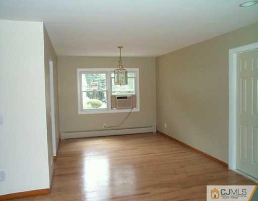 833 Inman Avenue Edison, NJ 08820 - Photo 5 of 8 an empty room with wooden floor chandelier and windows